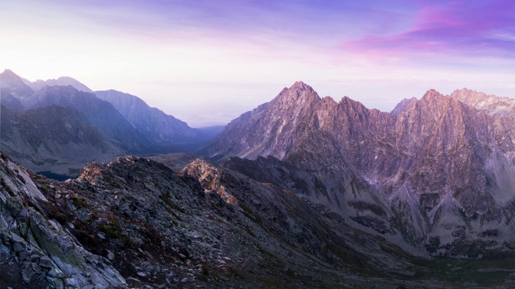 Stunning view of a rocky mountain range during sunrise with a colorful sky.