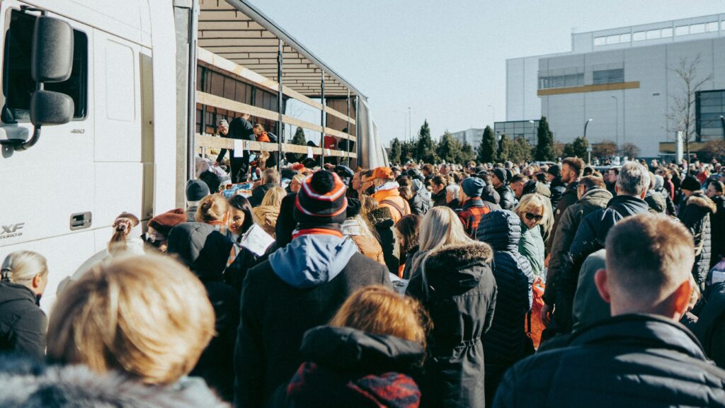 A large crowd gathers outside near a truck, participating in a rally event in Vilnius.