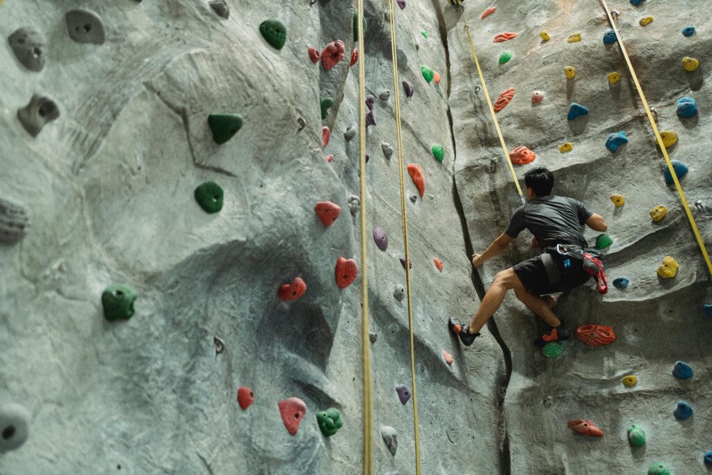 A man engaged in indoor rock climbing on a colorful gym wall, showcasing fitness and thrill.