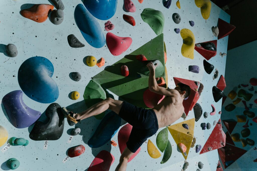 pexels-photo-6700281-6700281 A man climbs a colorful, challenging bouldering wall at an indoor gym, focused on training.