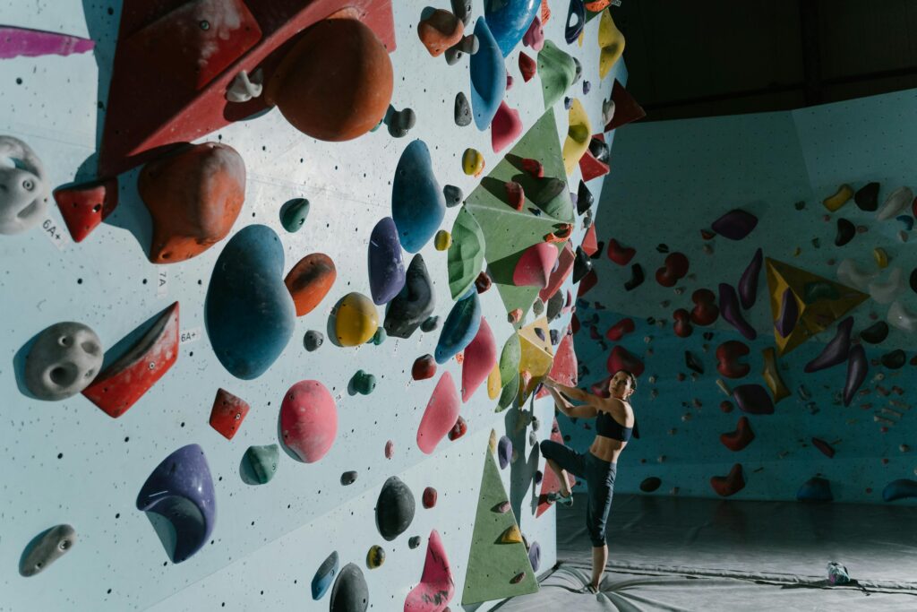 pexels-photo-6700633-6700633 Woman bouldering on a colorful indoor climbing wall, wearing activewear.